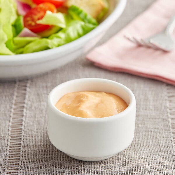 A white Tuxton ramekin filled with yellow sauce.