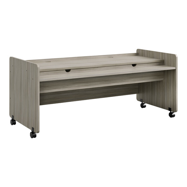 A Tot Mate Shadow Elm laminate mobile desk with wheels and a drawer.