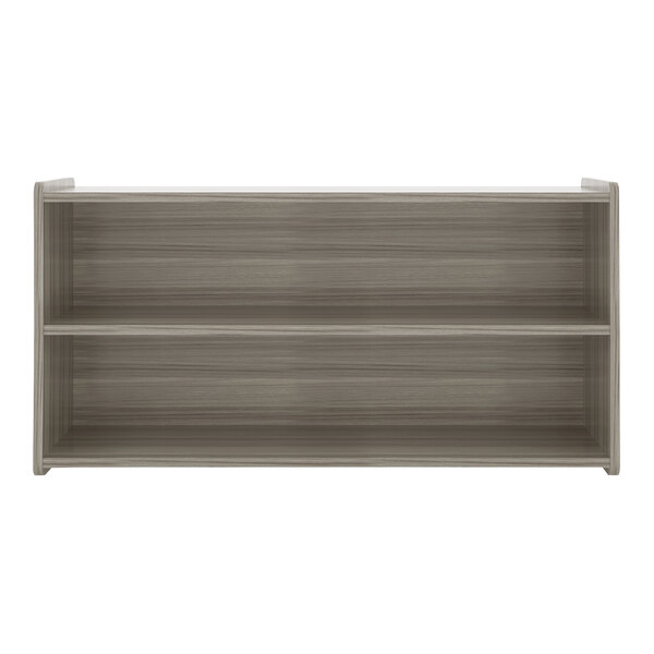 A Tot Mate shadow elm laminate toddler storage shelf with two shelves.