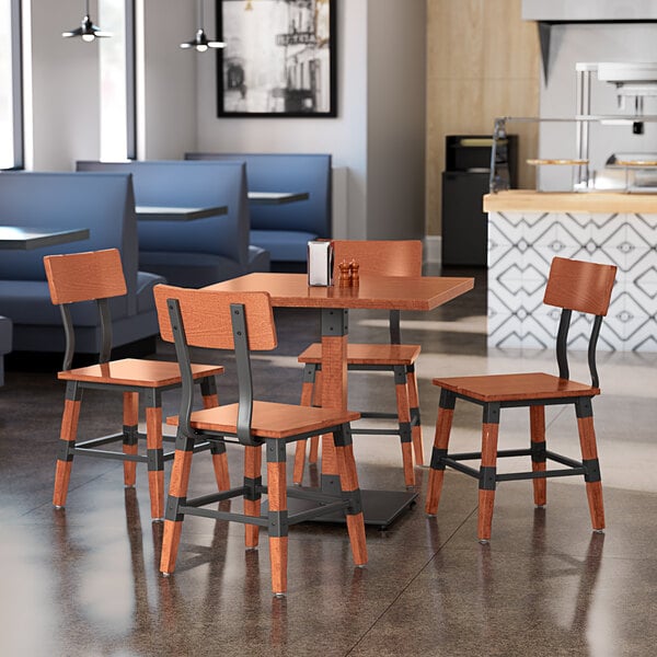 A Lancaster Table & Seating standard height table and chairs with a rustic mahogany finish in a restaurant.