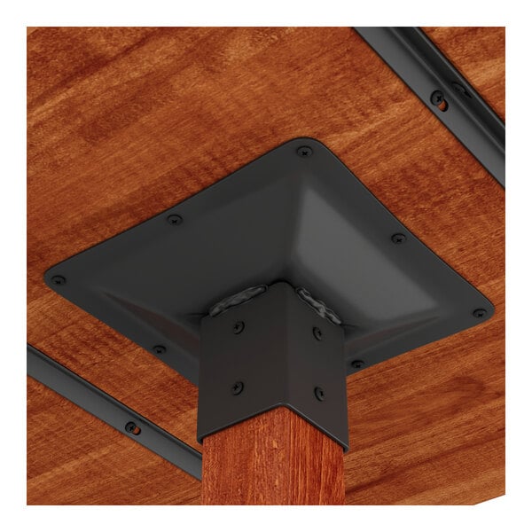 A close-up view of the underside of a wooden table showing a metal bracket securing a table leg.