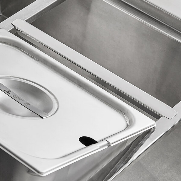 A stainless steel counter with a ServIt Heavy-Duty Steam Table Pan Adapter Bar on it.