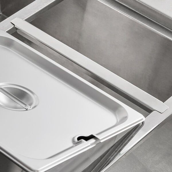 A stainless steel Avantco steam table adapter bar on a metal tray.