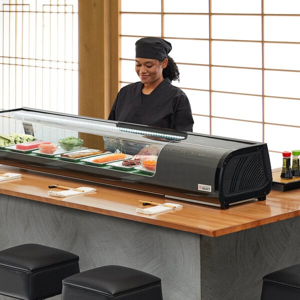 Employee standing behind a refrigerated sushi case