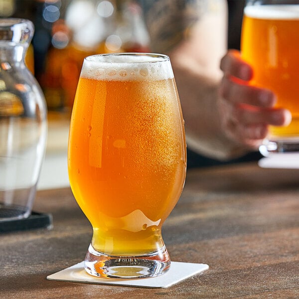 A glass of wheat beer on a table with a coaster.