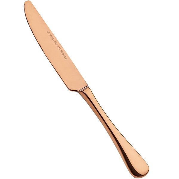 A Bon Chef stainless steel dinner knife with a rose gold handle on a counter.