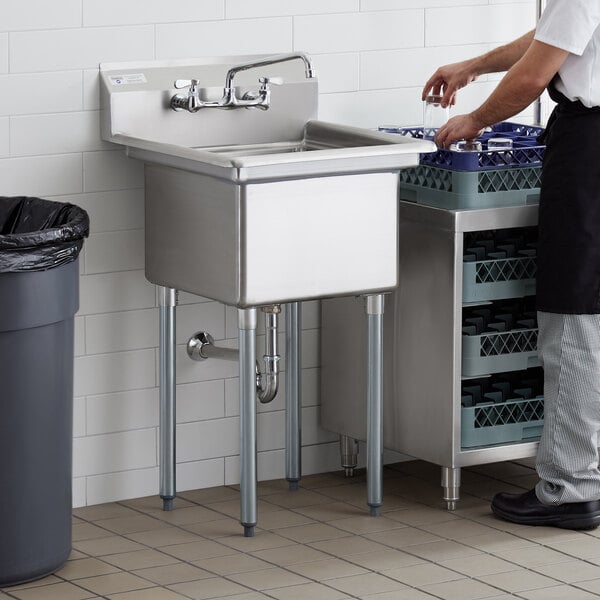 A man in a white shirt standing next to a Steelton stainless steel one compartment sink on a counter.