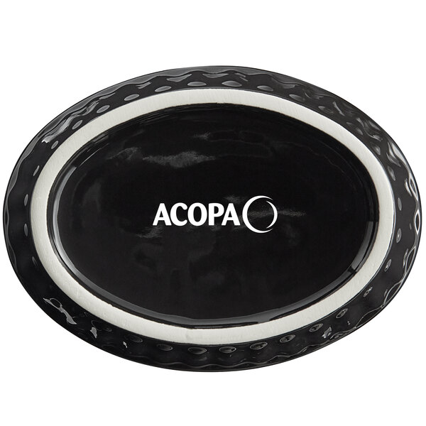 An oval black Acopa stoneware dish with fluted edges and white text.