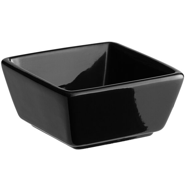 An Acopa black square stoneware sauce cup on a counter.