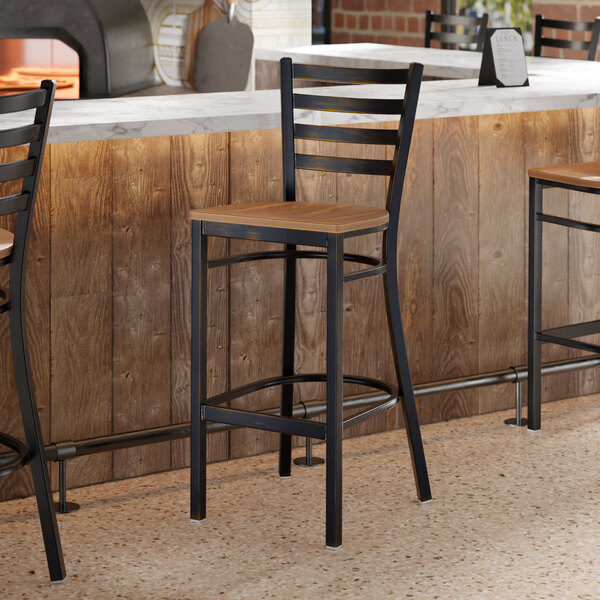 A ladder back bar stool with a distressed copper finish and a vintage wood seat.