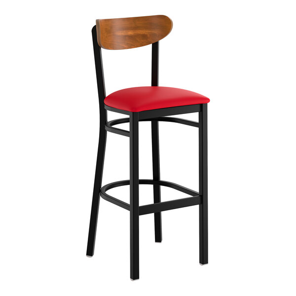 A bar stool with a black metal frame, red vinyl seat, and a curved wooden backrest.