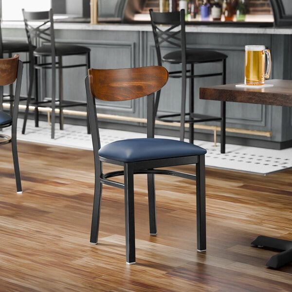 A black metal chair with a navy vinyl seat and a curved vintage wood backrest.