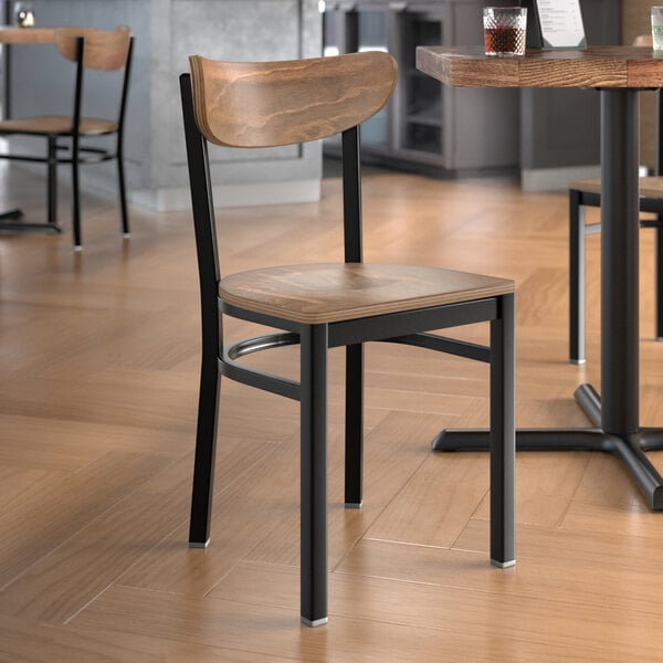 A Lancaster Table & Seating black metal chair with a wooden seat and back on a table in a restaurant.