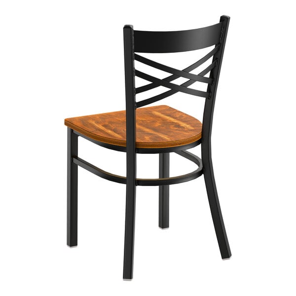 A black metal cross back chair with a vintage wood seat.