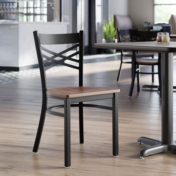A black metal cross back chair with a vintage wood seat.