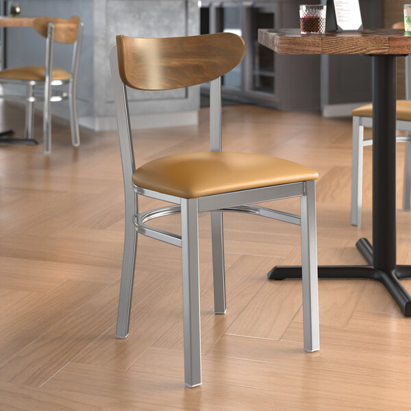 A Lancaster Table & Seating Boomerang chair with a light brown vinyl seat and vintage wood back.