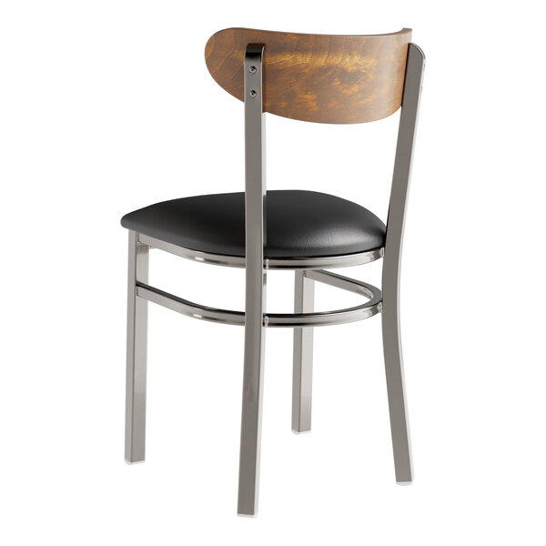A Lancaster Table & Seating Boomerang wood chair with a black vinyl seat.