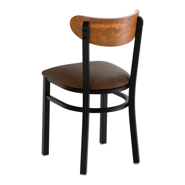 A black metal chair with a dark brown vinyl seat and a curved vintage wood backrest.