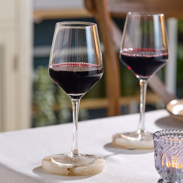 Two Acopa Silhouette wine glasses on a table with a glass of red wine.