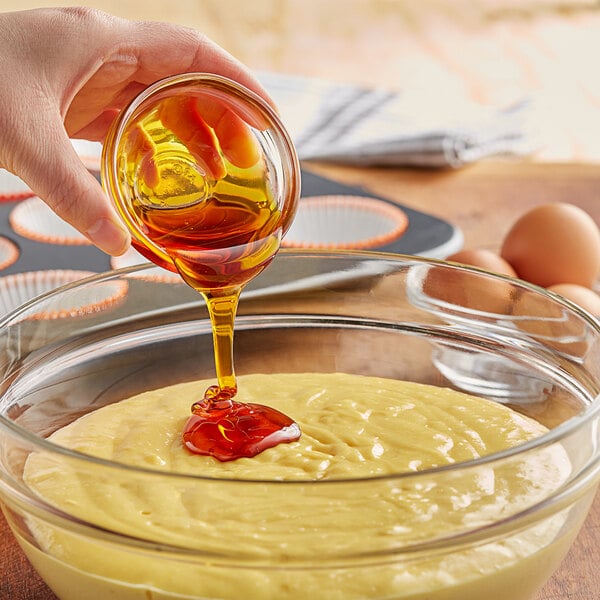 A person pouring LorAnn Oils Liquid Soy Lecithin into a bowl of dough.