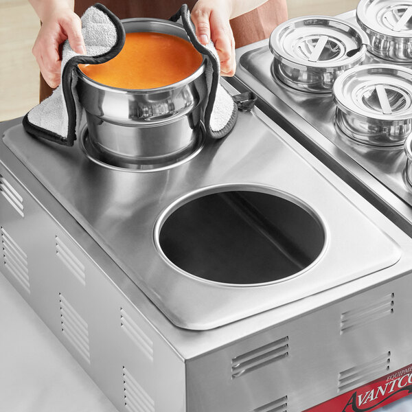 A person using an Avantco steam table adapter plate to prepare soup on a stove.