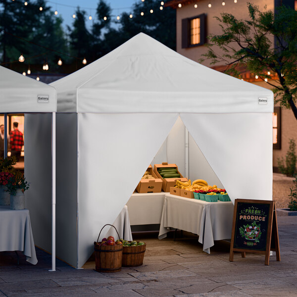 A white 10' x 10' pop-up canopy tent with four side walls set up at an outdoor market.