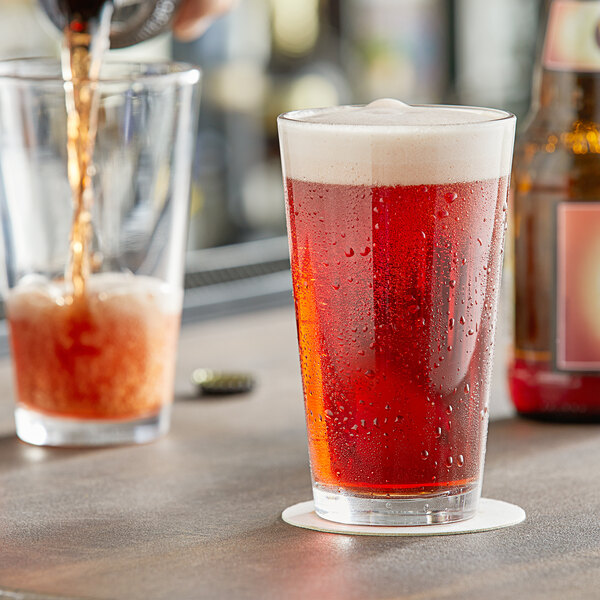 Arcoroc ArcoPrime pint glass of beer being poured on a table in a bar.