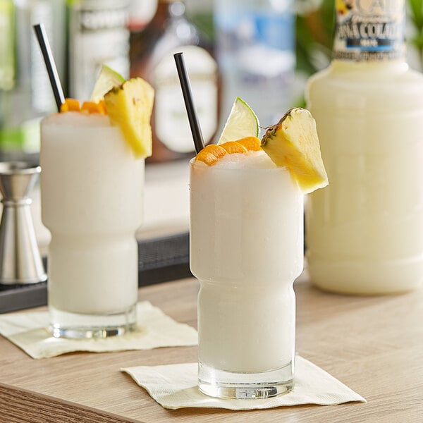 Two pina coladas garnished with pineapple