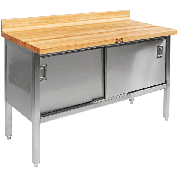 A wood top work table with stainless steel sliding doors.