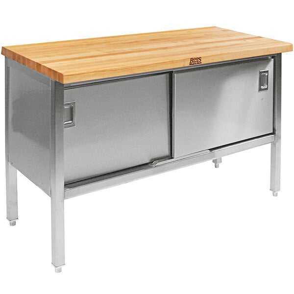 A John Boos wood top work table with stainless steel base and sliding doors.