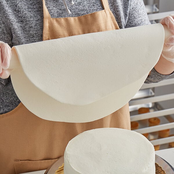 A woman using Satin Ice Dream white chocolate-flavored fondant on a cake.