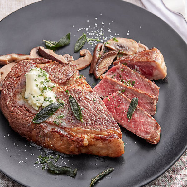 A plate of Kinikin Processing Rocky Mountain dry-aged ribeye steak with mushrooms and herbs.