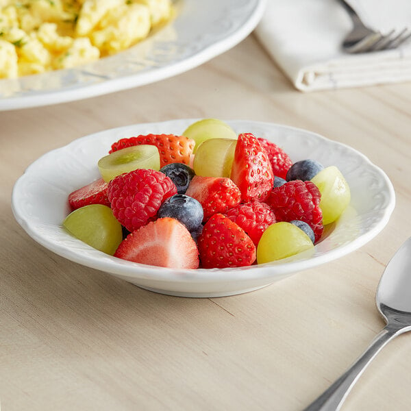 A Tuxton bright white china monkey dish filled with fruit on a table.