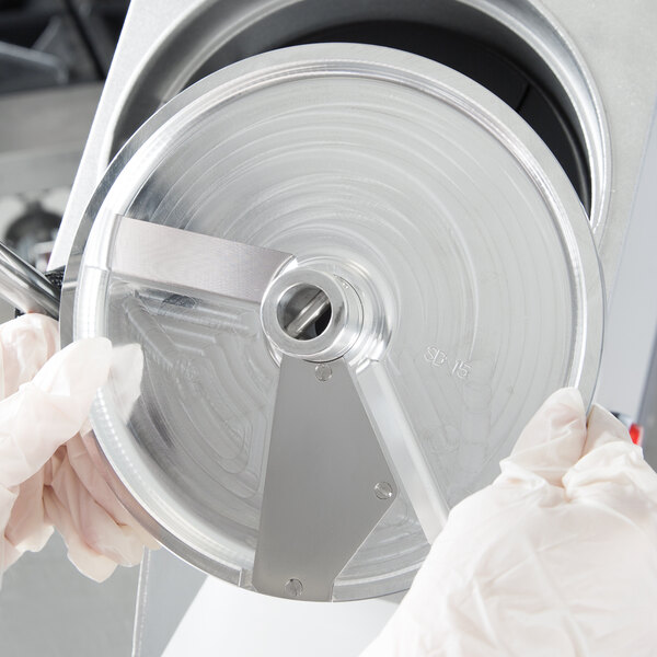 A person in white gloves using a Hobart 5/8" soft slicing plate to cut food.