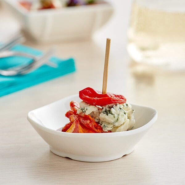 A small white Tablecraft mini melamine bowl with food in it on a table.