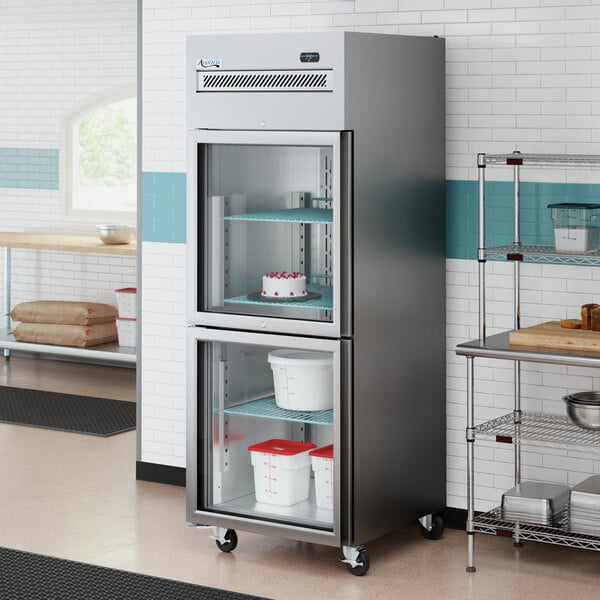 A stainless steel reach-in refrigerator with two left-hinged glass half doors and interior shelving.