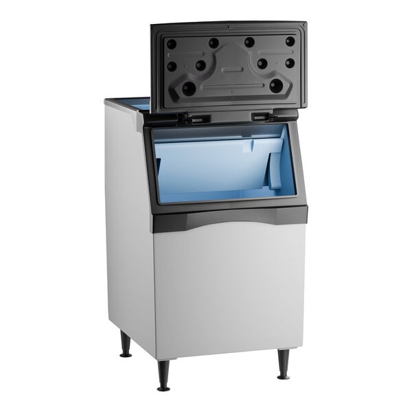 A rectangular ice storage bin with a plastic exterior, standing on four legs, featuring an open top lid and a blue interior.