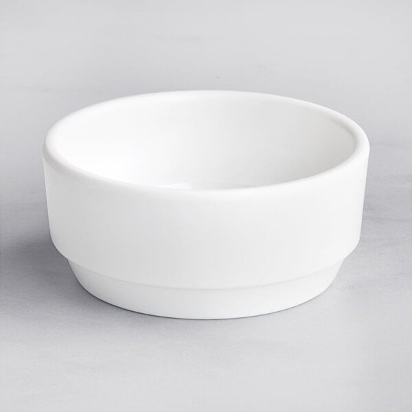 A Tablecraft round white melamine bowl on a gray surface.