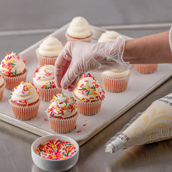 A finger holding a cupcake with Rich's Bettercreme cream cheese whipped frosting and sprinkles.