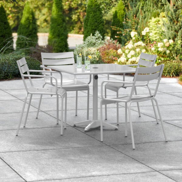 A Lancaster Table & Seating silver aluminum dining table with chairs on an outdoor patio.