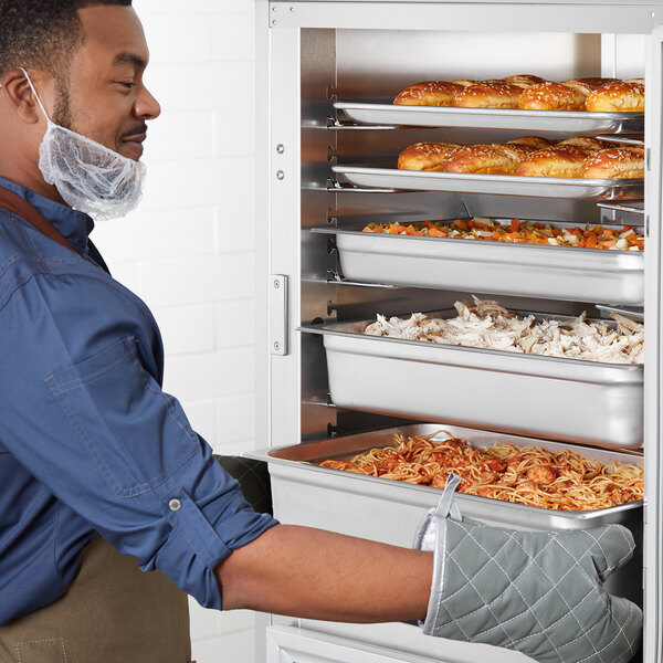 A man opening the solid dutch doors of a ServIt holding and proofing cabinet on a counter.