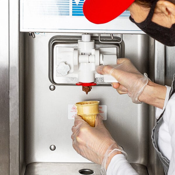 Person dispensing chocolate ice cream from a soft serve machine