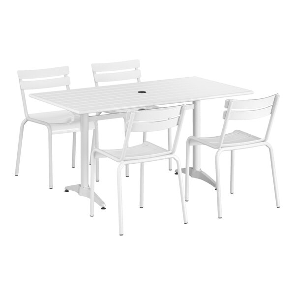 A white Lancaster Table & Seating dining table with 4 chairs and an umbrella hole.