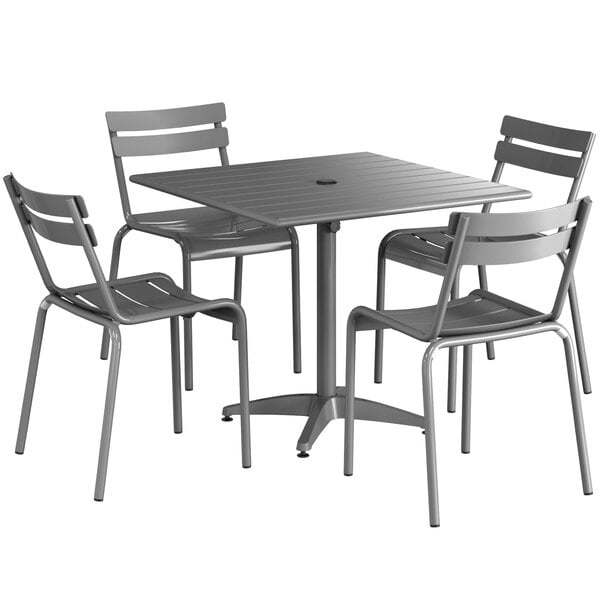 A Lancaster Table & Seating matte gray aluminum dining table with chairs set around it.