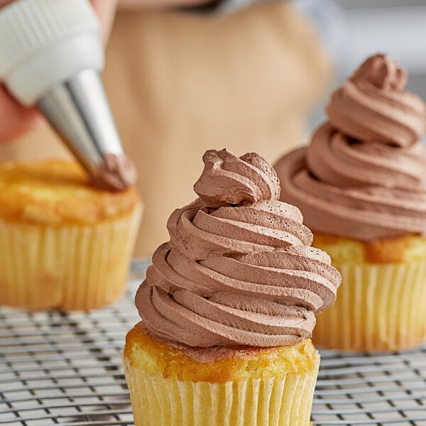 A person decorating a cupcake with Rich's Double Rich Chocolate whipped icing.