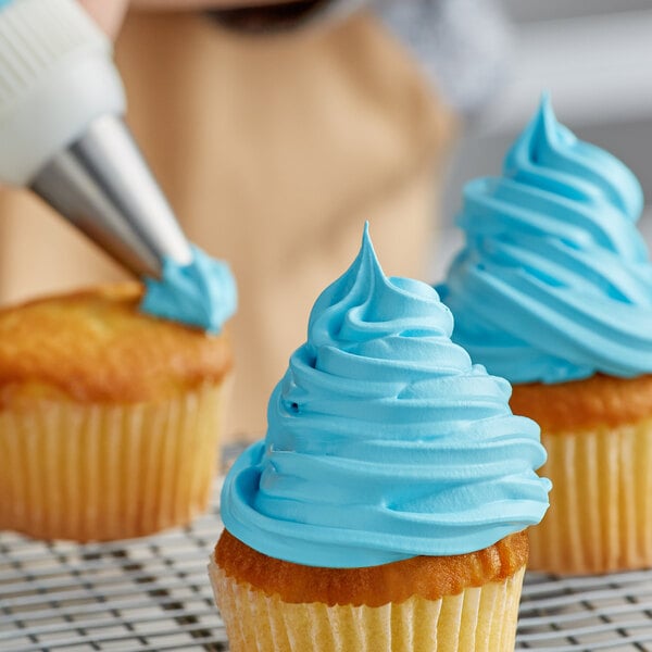 A person decorating a cupcake with Rich's Bettercreme blue whipped icing.