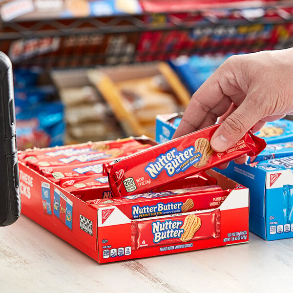 A hand holding a red package of Nabisco Nutter Butter cookies.