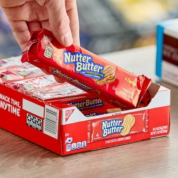 A hand holding a red package of Nabisco Nutter Butter cookies.