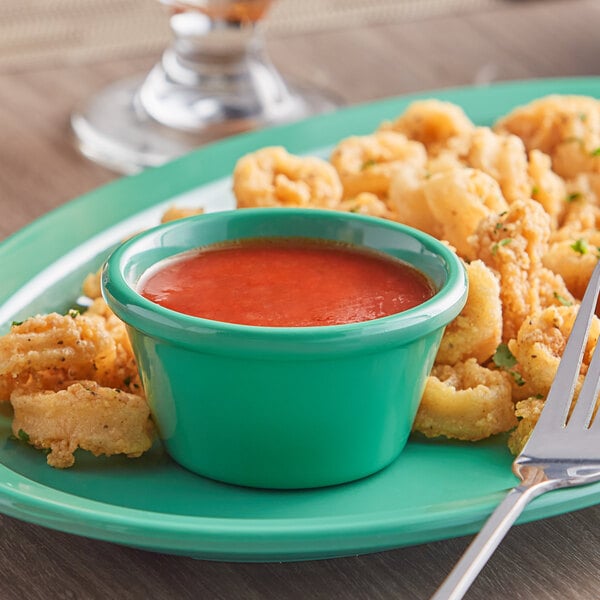 A plate of fried food with an Acopa green smooth ramekin of sauce.