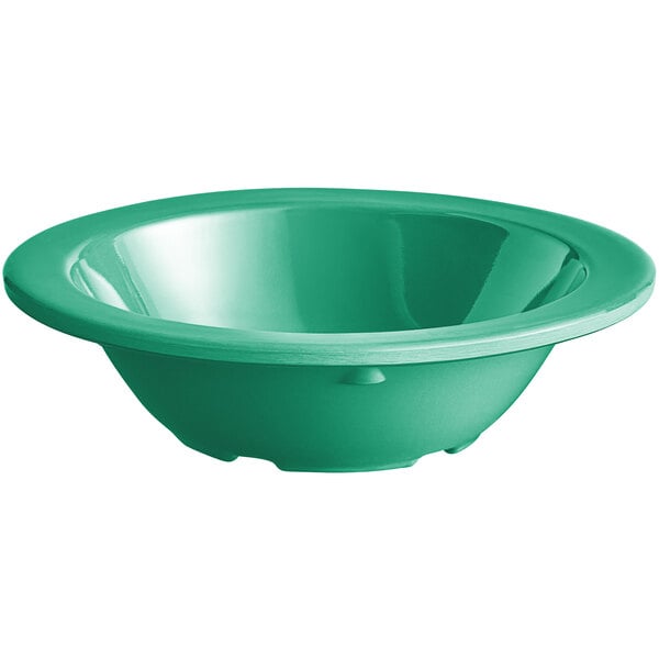 A close up of a green Acopa Foundations melamine fruit bowl.